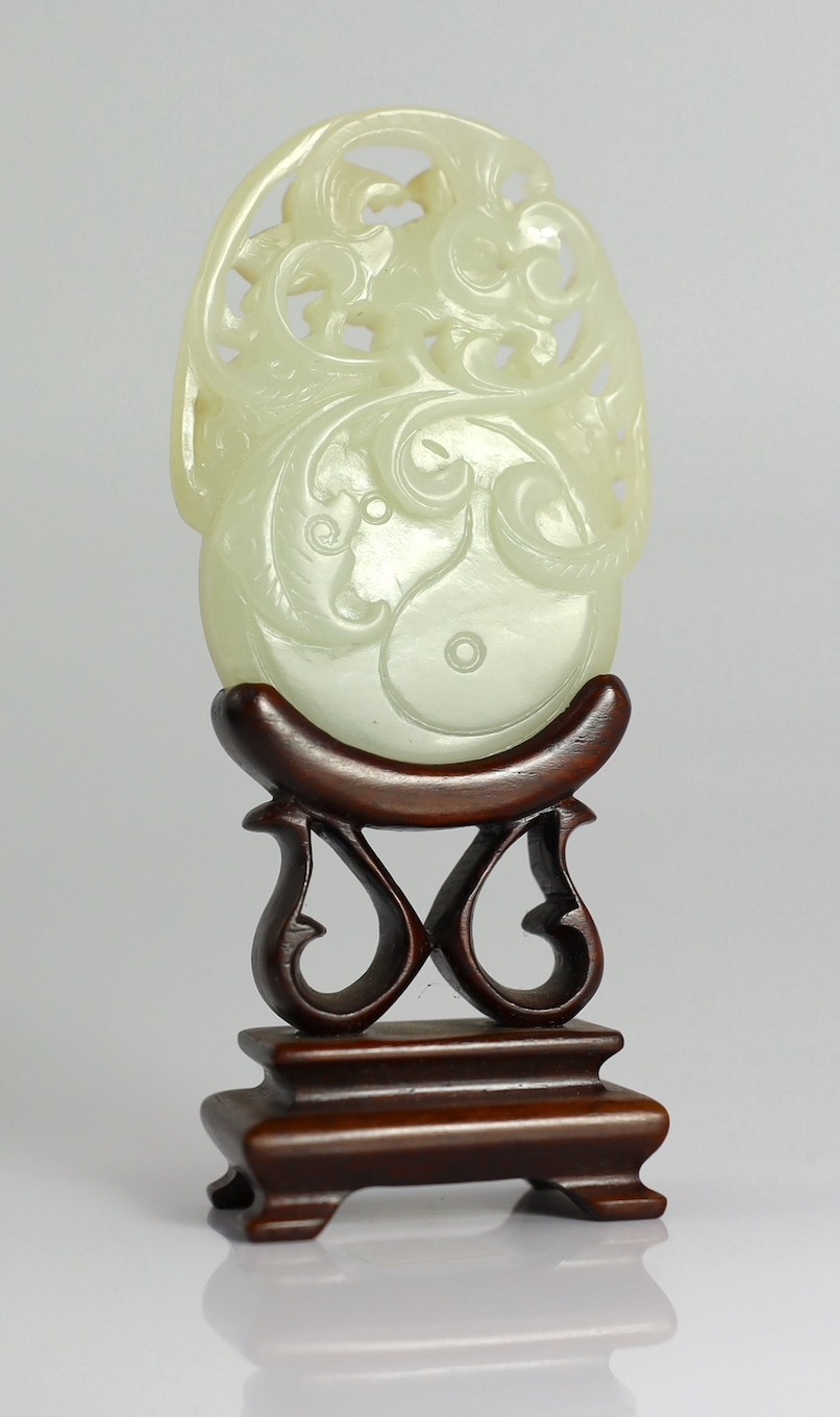 A Chinese white and russet skin jade oval plaque, 19th century, 6.4cm, wood stand